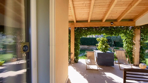 panoramica del portico e del giardino con sdraio e sedie di legno